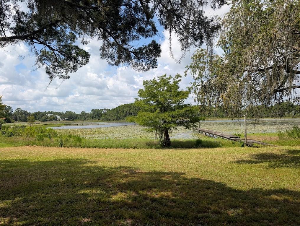 A screened-in porch with a wood-plank ceiling, carpeted floor, and outdoor furniture overlooking a yard — 348 MITNIK DRIVE, DELTONA, FL
