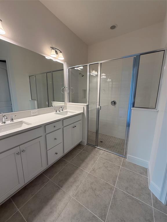 A bathroom with a double vanity, white cabinets, a large mirror, and a glass-enclosed shower — 2315 DATURA LOOP, ST CLOUD, FL