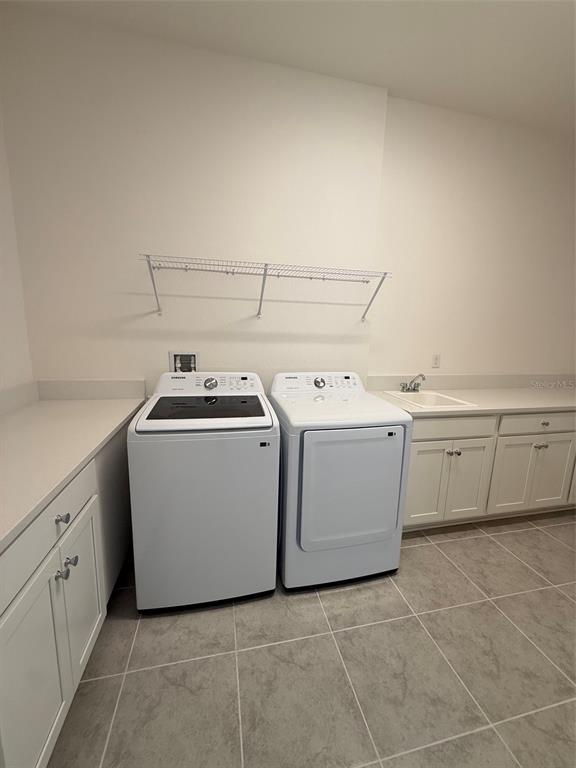 A laundry room featuring white cabinets, a utility sink, and a washer and dryer set — 2315 DATURA LOOP, ST CLOUD, FL