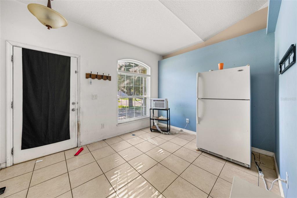 A room with tiled floors, a white refrigerator, a window, and a door with a cover — 7865 PINE FORK DRIVE, ORLANDO, FL