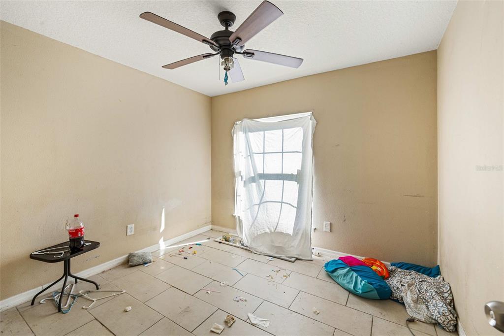 An empty room with beige walls, tile flooring, a ceiling fan, and a window — 7865 PINE FORK DRIVE, ORLANDO, FL