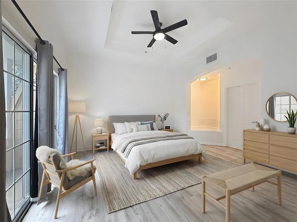 A modern bedroom features a bed, a ceiling fan, a wooden dresser, and a seating area — 7510 SEVEN EAGLES WAY, KISSIMMEE, FL