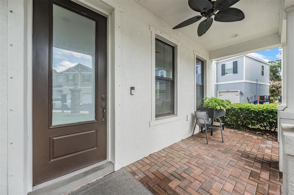 A covered brick porch features a brown front door, a ceiling fan, and a chair — 845 AURORA WAY, OLDSMAR, FL