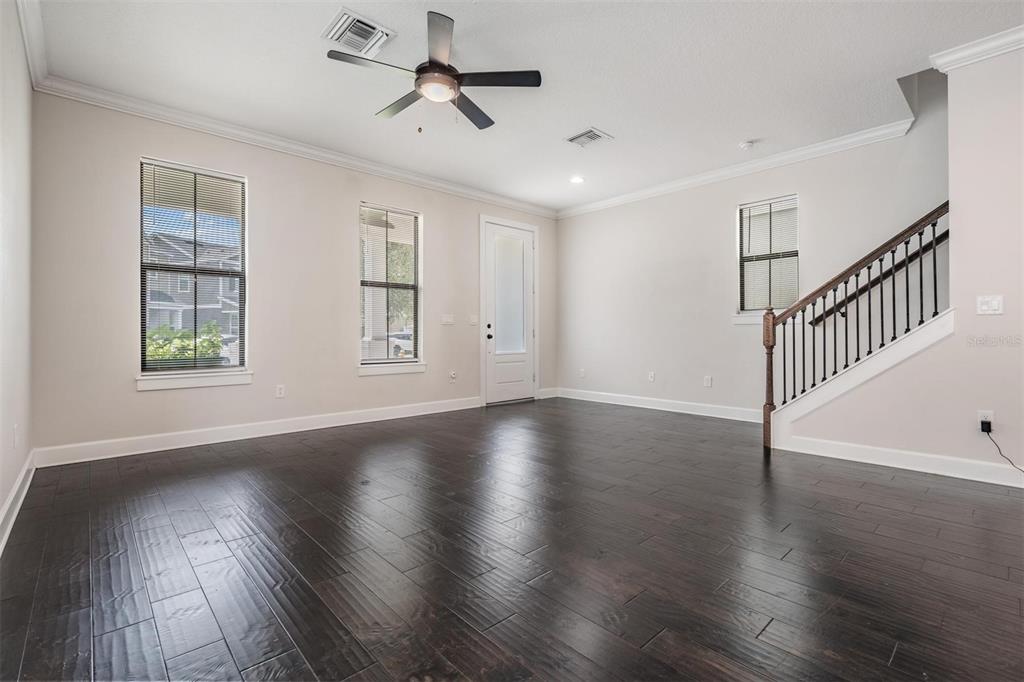 An empty living room features dark hardwood floors, light walls, a ceiling fan, and stairs — 845 AURORA WAY, OLDSMAR, FL