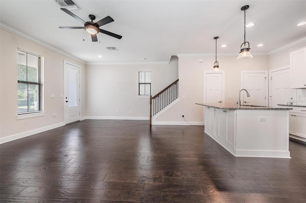 An open-concept living area features dark wood flooring, a kitchen island, and a staircase — 845 AURORA WAY, OLDSMAR, FL
