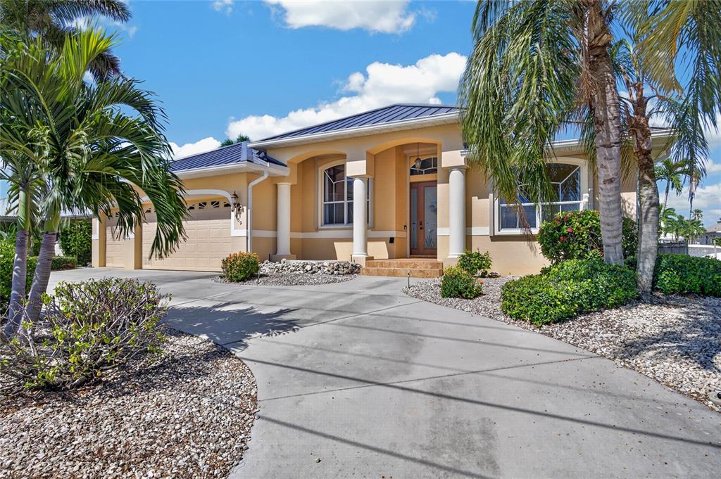 A single-story house with a tan stucco exterior, metal roof, and a concrete driveway — 959 BAL HARBOR BOULEVARD, PUNTA GORDA, FL