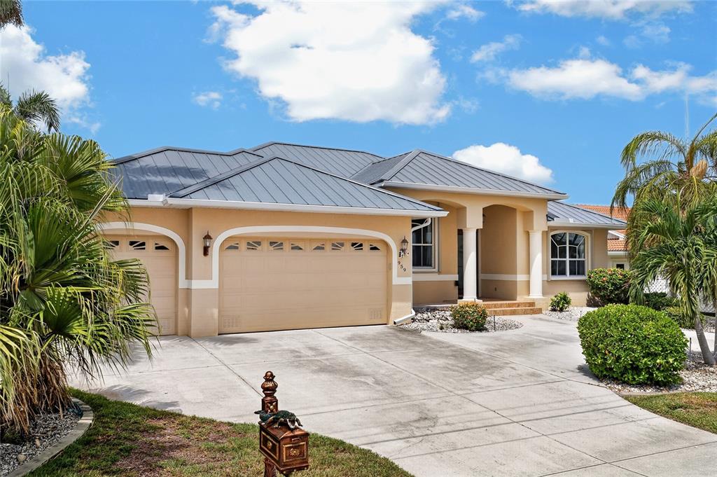 A single-story house with a metal roof, tan stucco exterior, and a three-car garage — 959 BAL HARBOR BOULEVARD, PUNTA GORDA, FL