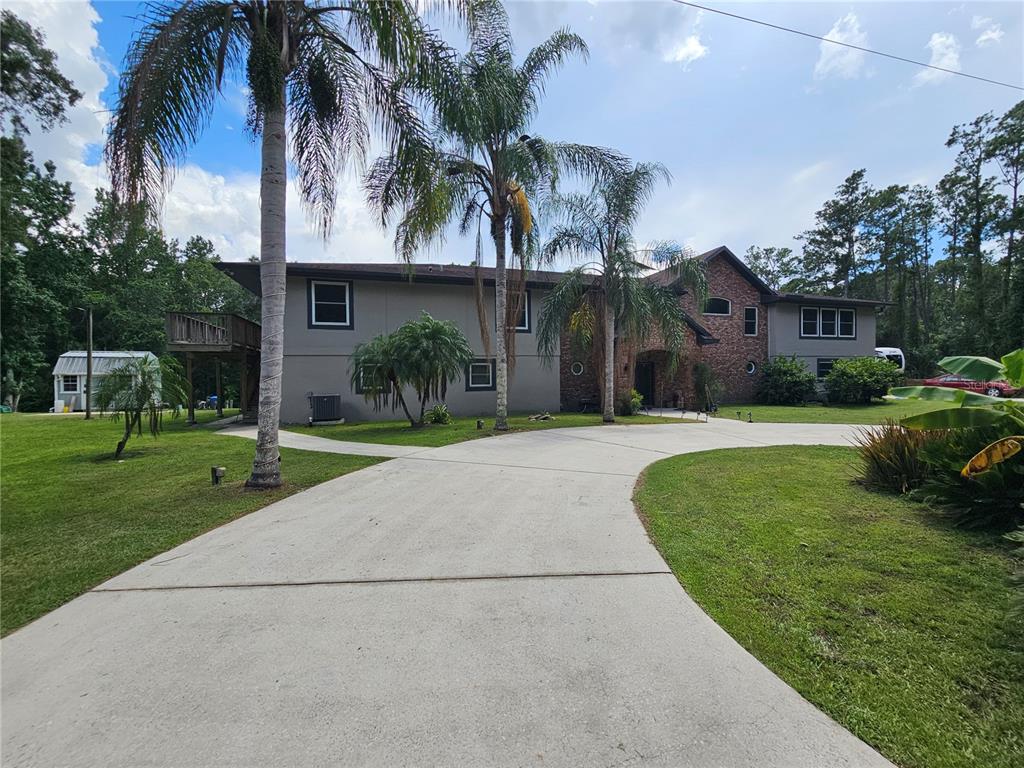 A two-story house with a brick facade, gray stucco walls, and a concrete driveway — 1607 MARTY DRIVE, PIERSON, FL