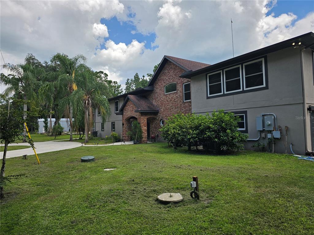 A two-story house with a brick facade, gray siding, and a large front lawn — 1607 MARTY DRIVE, PIERSON, FL