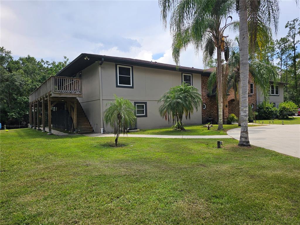 A two-story house with a wooden deck and staircase stands on a grassy lawn — 1607 MARTY DRIVE, PIERSON, FL