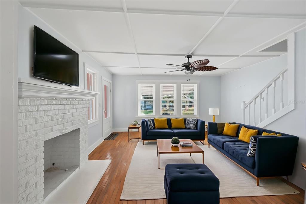 A living room features a white brick fireplace, blue sofas, and a coffered ceiling — 10 PLAZA STREET E, BRADENTON, FL