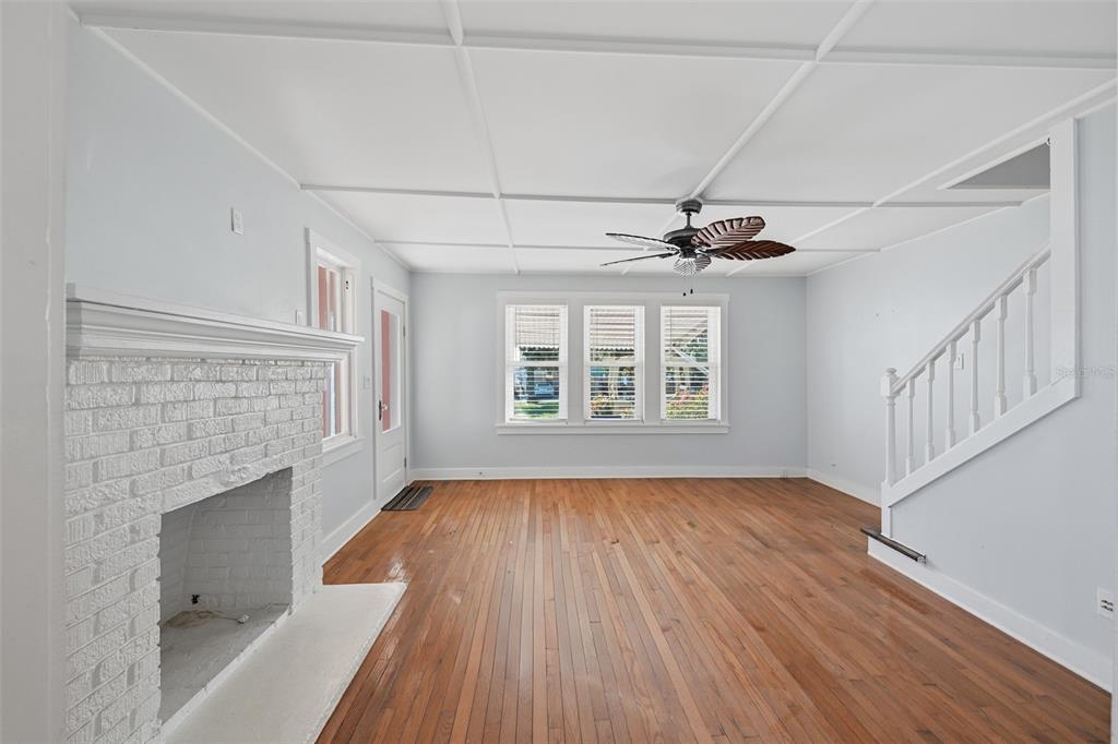 A living room features a white brick fireplace, hardwood floors, and a staircase — 10 PLAZA STREET E, BRADENTON, FL
