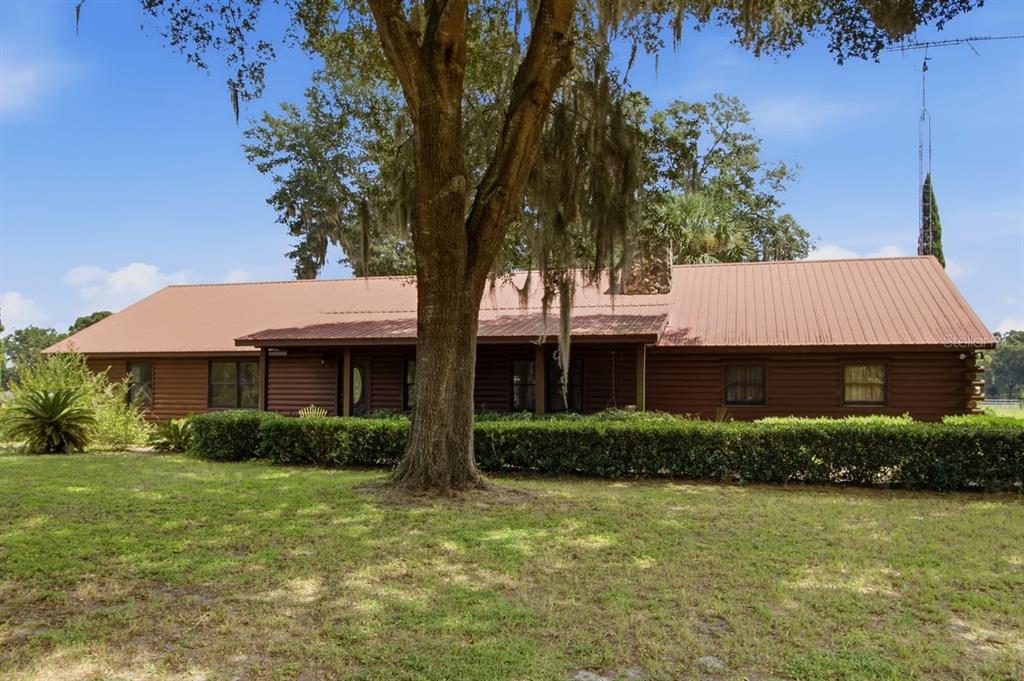 A single-story log cabin home features a metal roof and a covered front porch — 2259 BROWNLEE ROAD, SEVILLE, FL
