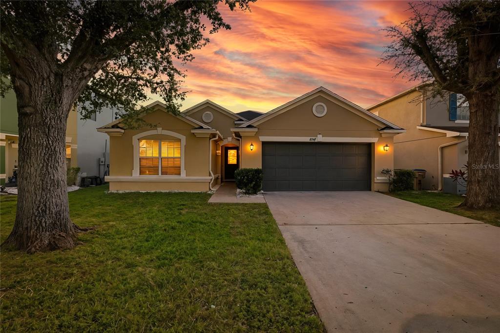 A single-story house with a tan exterior, a two-car garage, and a concrete driveway — 4647 CAVERNS DRIVE, KISSIMMEE, FL