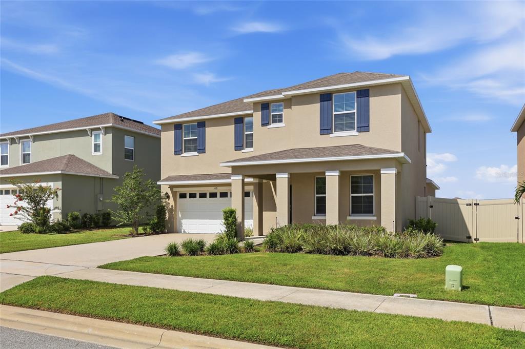 A two-story suburban house with a tan stucco exterior, a two-car garage, and a lawn — 1481 KEMPAS ROAD, MOUNT DORA, FL