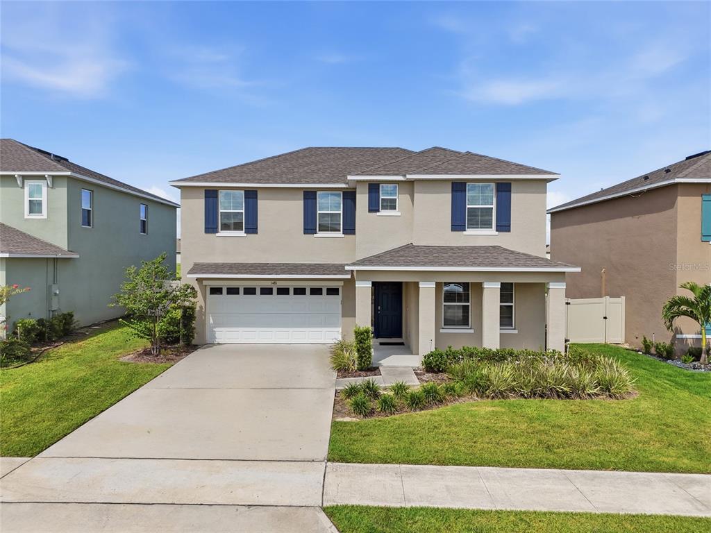 A two-story suburban house with a beige stucco exterior, dark shutters, and a two-car garage — 1481 KEMPAS ROAD, MOUNT DORA, FL