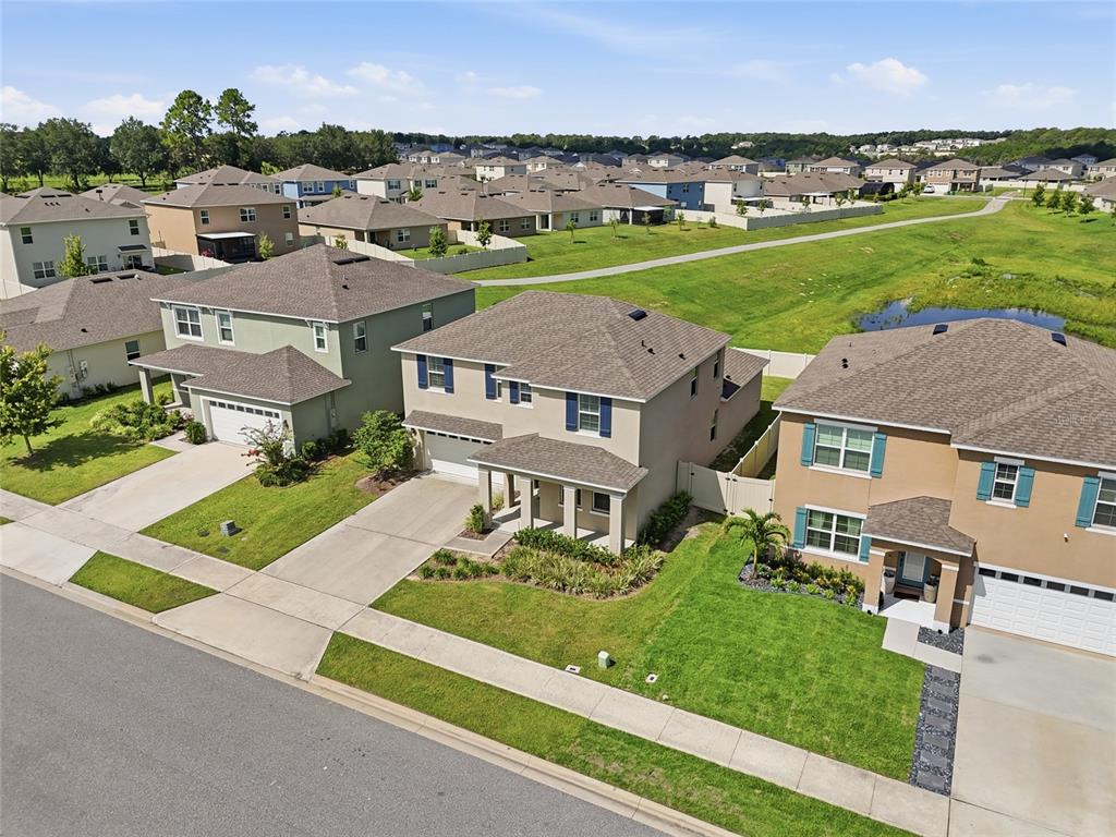 An aerial view shows three suburban houses with driveways and lawns near a retention pond — 1481 KEMPAS ROAD, MOUNT DORA, FL