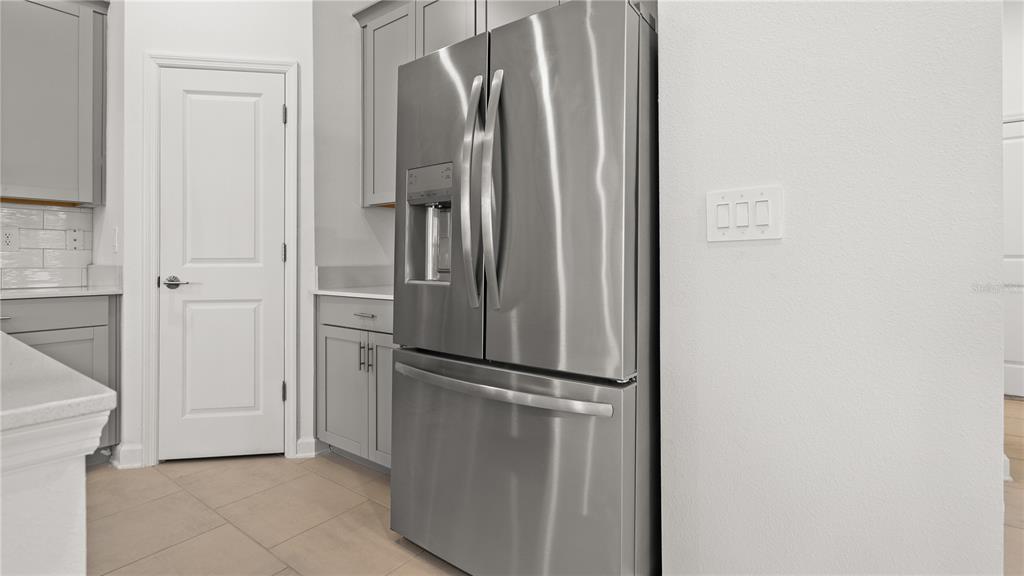 A kitchen features gray cabinets, a stainless steel refrigerator, and a white door — 4103 EASTMINSTER ROAD, DAVENPORT, FL