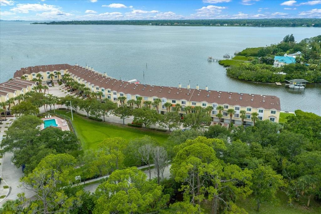 An aerial view shows a long waterfront townhouse complex with a pool and green space — 158 BRENT CIRCLE, OLDSMAR, FL