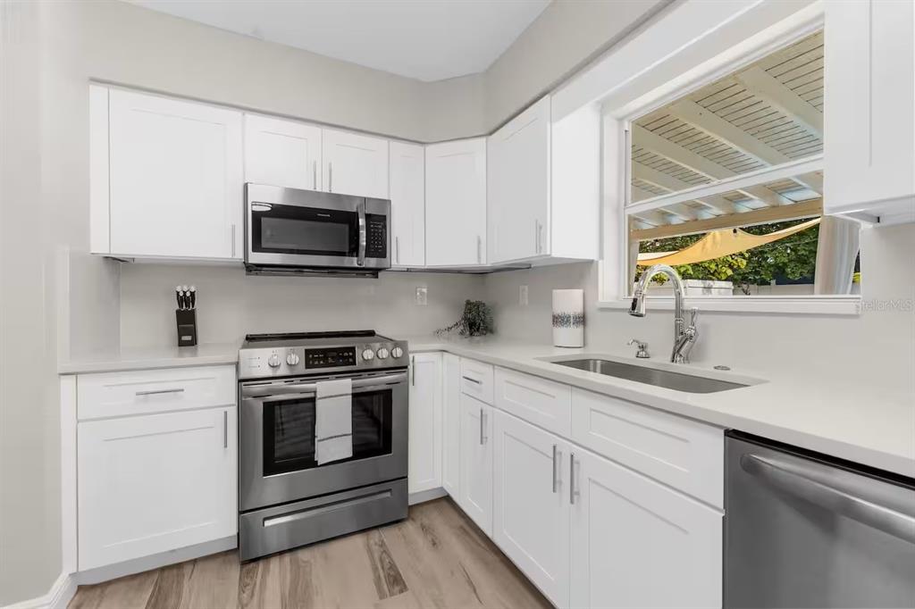 A kitchen with white cabinets, stainless steel appliances, and a window above the sink — 8215 QUAIL ROAD, SEMINOLE, FL
