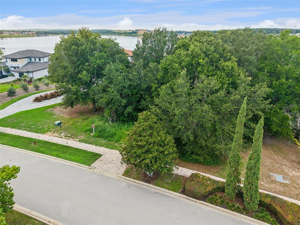 An elevated view shows a vacant, tree-covered residential lot situated next to a lake — 15345 PENDIO DRIVE, MONTVERDE, FL