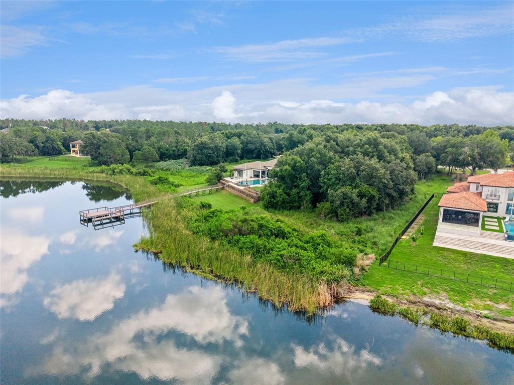 An aerial view shows two houses near a lake with a wooden dock and trees — 15345 PENDIO DRIVE, MONTVERDE, FL