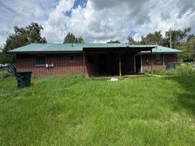 A single-story brick house with a green metal roof and a covered patio area — 119 N WEST STREET, BUSHNELL, FL