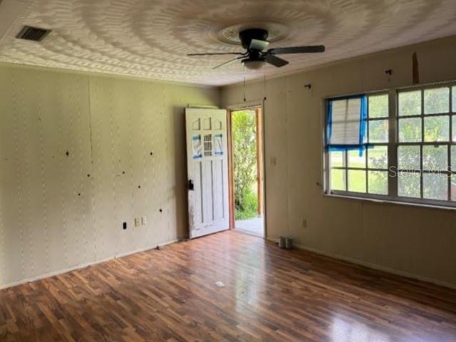 An interior room with wood-look flooring, a ceiling fan, a white door, and large windows — 119 N WEST STREET, BUSHNELL, FL