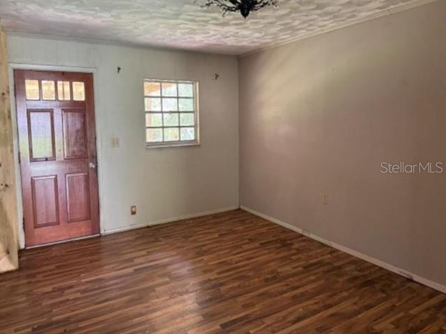 An interior room features wood-look flooring, a brown front door, and a single window — 119 N WEST STREET, BUSHNELL, FL