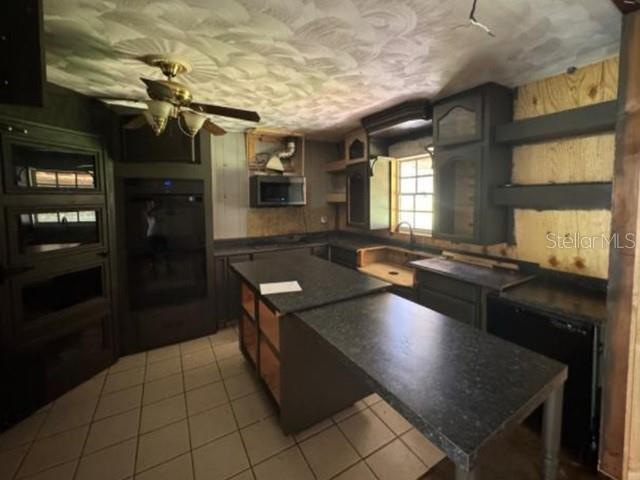 A kitchen features dark cabinets, a central island, a ceiling fan, and unfinished wall sections — 119 N WEST STREET, BUSHNELL, FL