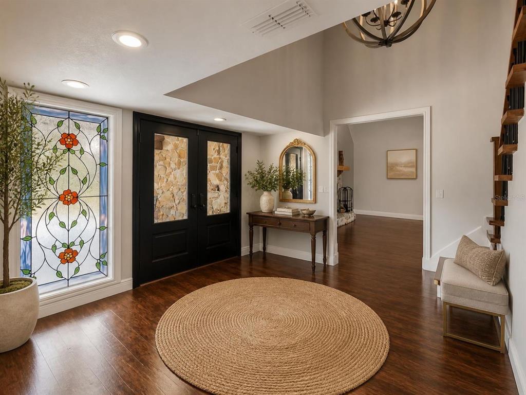 A foyer features a round jute rug, dark wood floors, a stained-glass window, and stairs — 2120 MARQUIS COURT, NEW PORT RICHEY, FL
