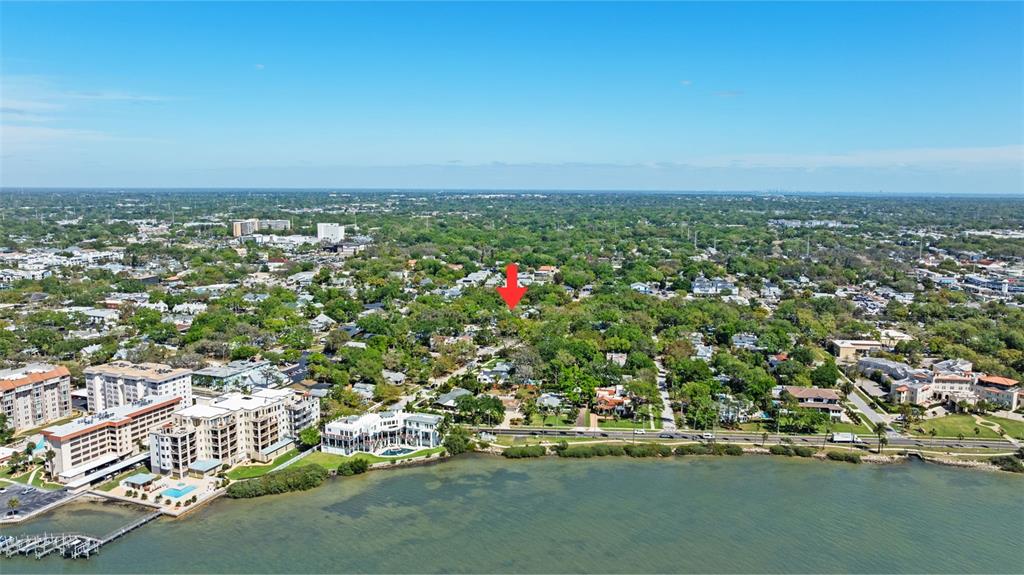 An aerial view shows a residential neighborhood along a waterfront with a red arrow pointing down — 300 PRESIDENT STREET, DUNEDIN, FL