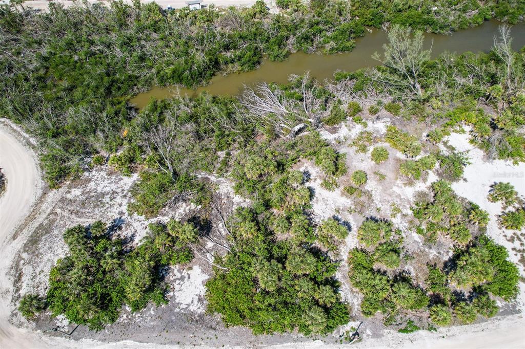 An aerial view shows a vacant, sandy lot with native vegetation bordering a small waterway — 6170 RUM COVE DRIVE, PLACIDA, FL