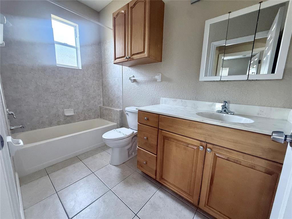 A bathroom features a vanity with a light countertop, a toilet, and a tiled tub — 9322 ANITA AVENUE, ENGLEWOOD, FL