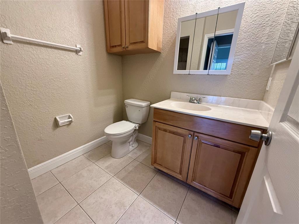 A bathroom features a wood vanity, a white countertop, a toilet, and a wall cabinet — 9322 ANITA AVENUE, ENGLEWOOD, FL