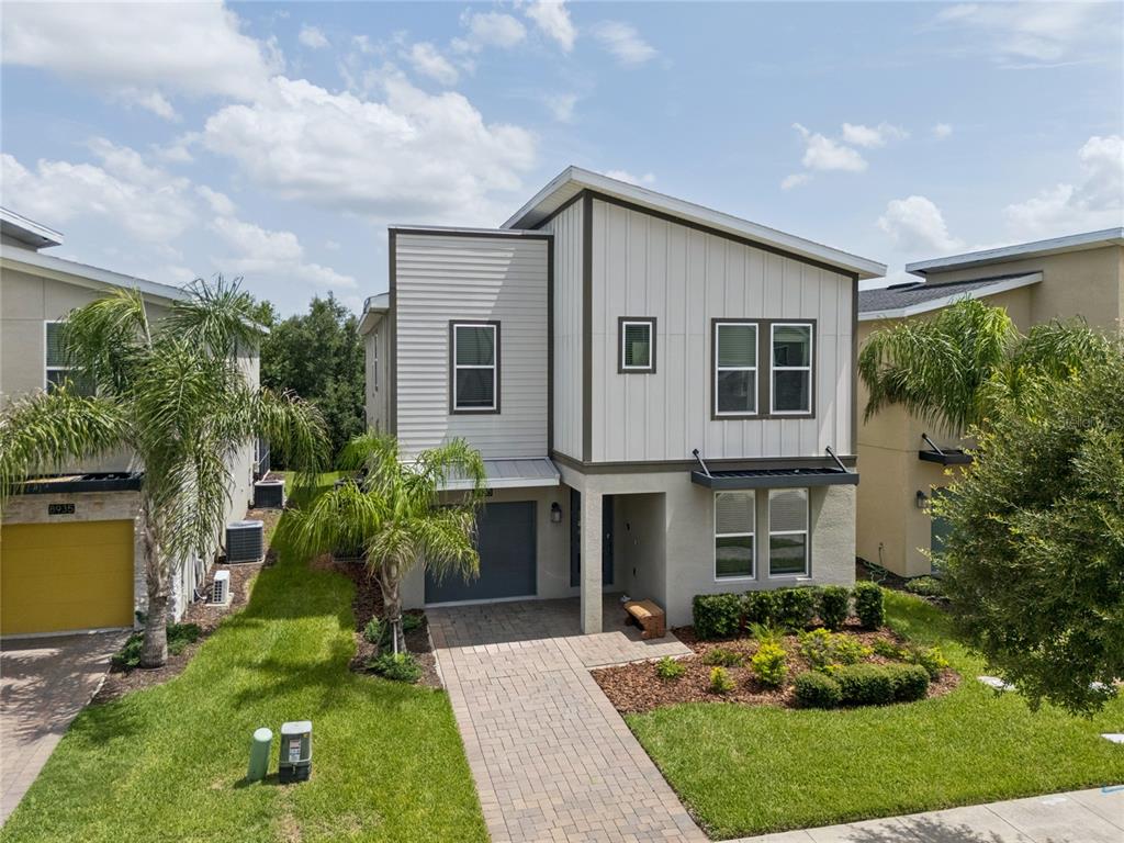 A two-story house with a modern shed roof, vertical siding, and a paved front walkway — 8933 CABOT CLIFFS DRIVE, DAVENPORT, FL