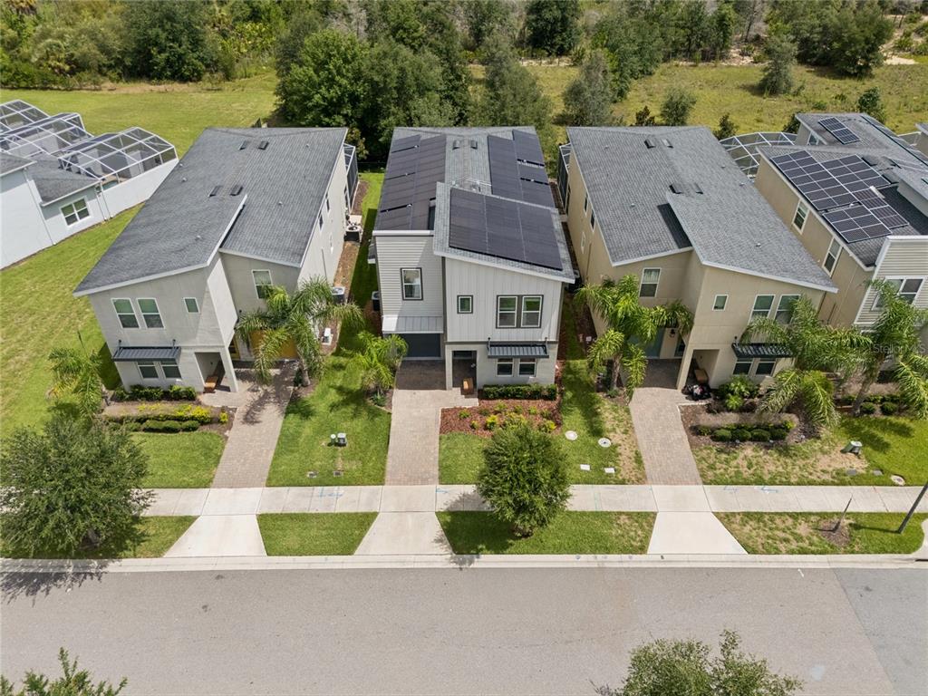 An aerial view shows three modern two-story houses with paved walkways and solar panels — 8933 CABOT CLIFFS DRIVE, DAVENPORT, FL