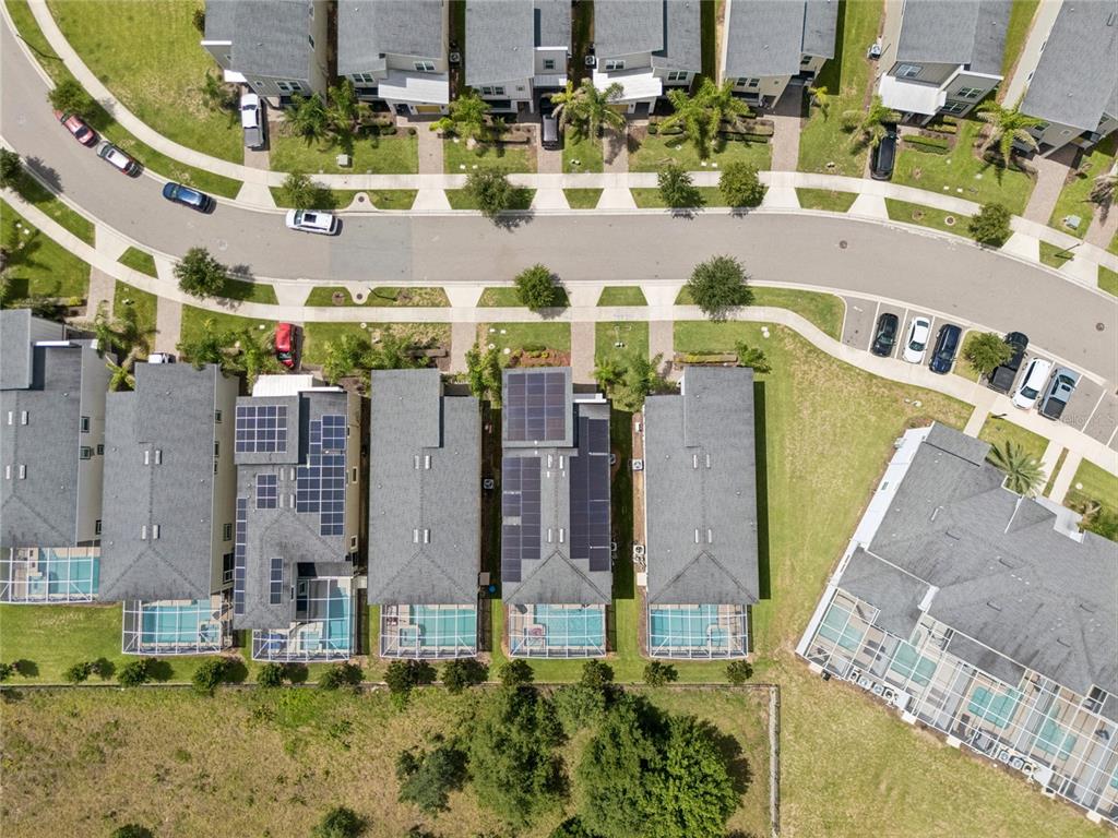 An aerial view shows a suburban street with townhouses, private swimming pools, and solar panels — 8933 CABOT CLIFFS DRIVE, DAVENPORT, FL