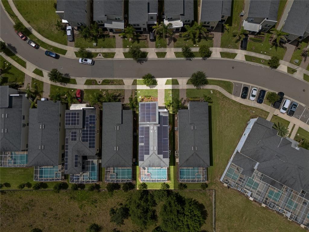 Aerial view of a residential neighborhood featuring a house with solar panels and a pool — 8933 CABOT CLIFFS DRIVE, DAVENPORT, FL