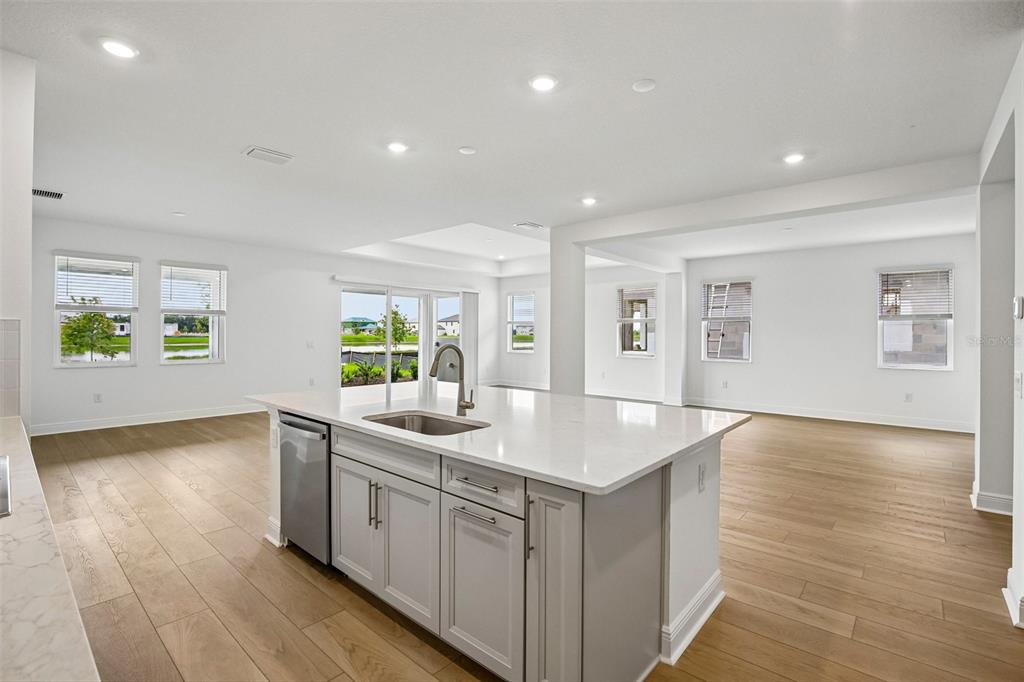 A kitchen island with a stainless steel sink and dishwasher sits in a bright open room — 7551 HAWKSTONE DRIVE, SARASOTA, FL
