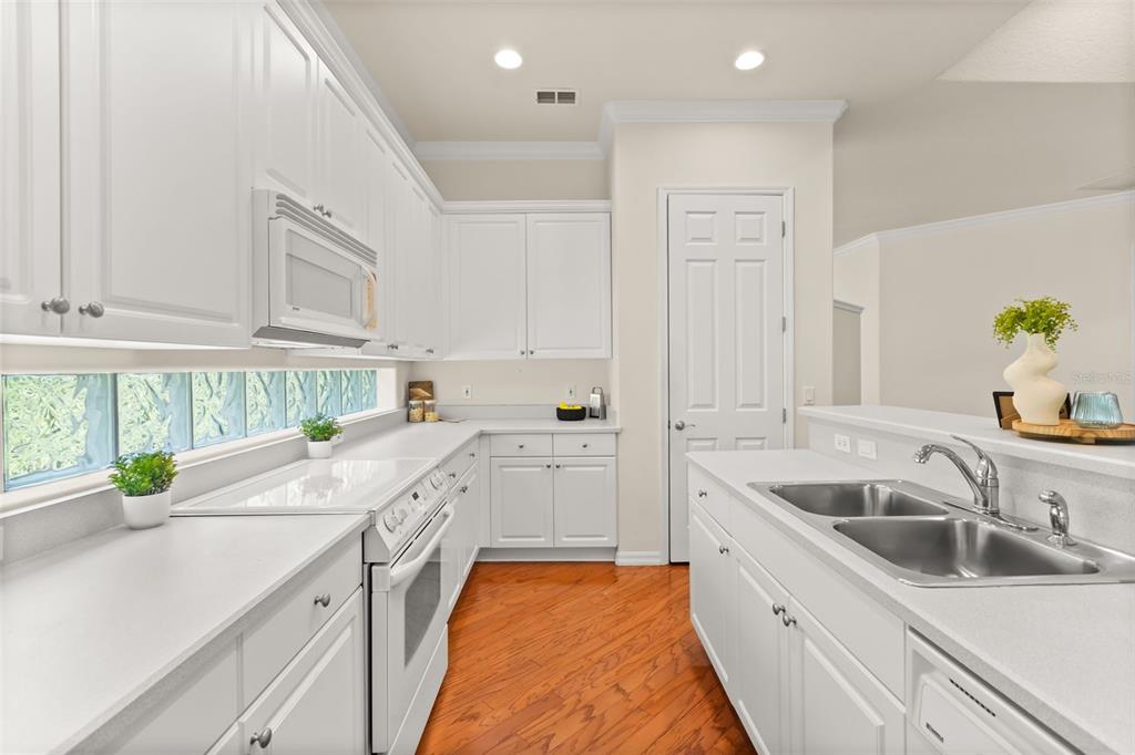 A kitchen with white cabinets, white countertops, a double sink, and hardwood flooring — 388 SOTHEBY WAY, DEBARY, FL