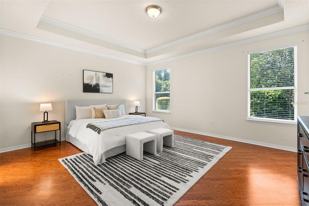 A bedroom with a tray ceiling, hardwood floors, a bed, and two windows — 388 SOTHEBY WAY, DEBARY, FL