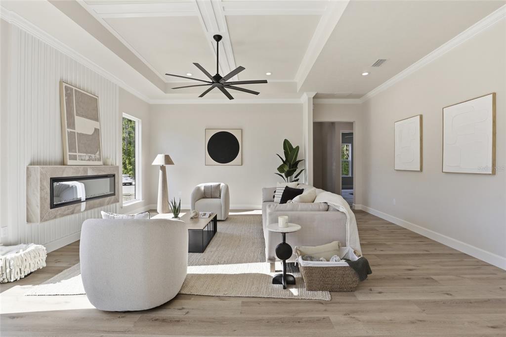 A modern living room features a fireplace, neutral furniture, a ceiling fan, and light wood flooring — 13425 SW 9TH ROAD, NEWBERRY, FL