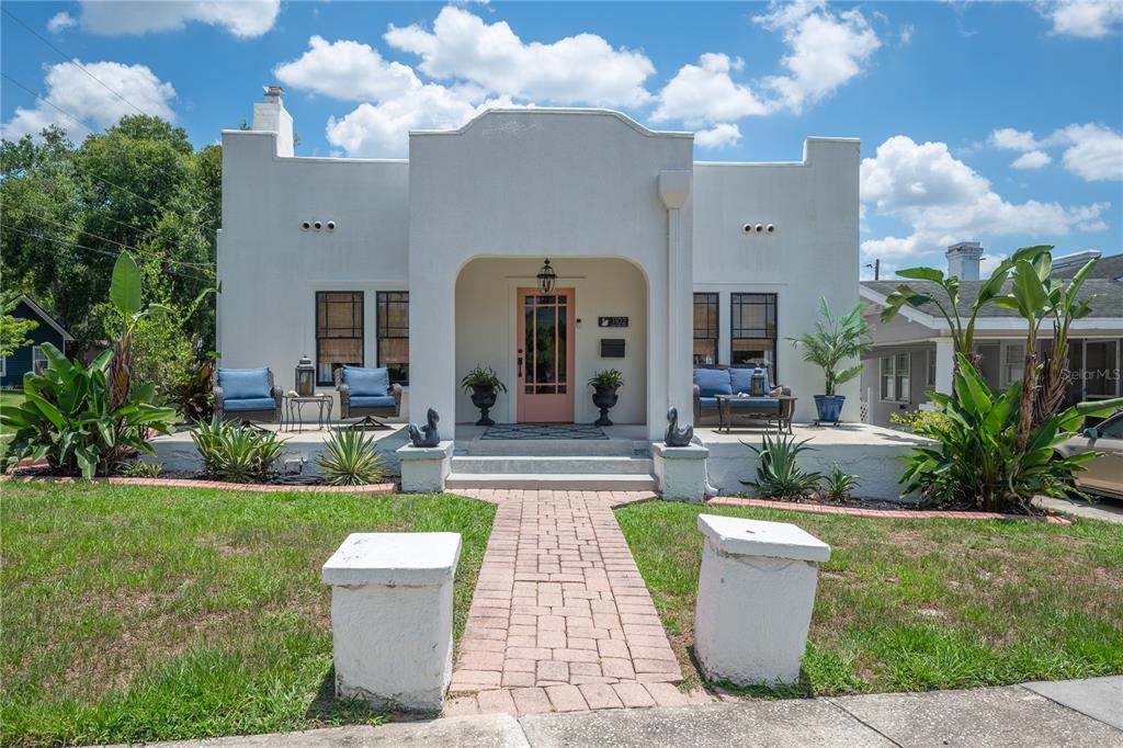A white stucco house with a flat roof, arched entryway, and a front porch — 1102 MELTON AVENUE, LAKELAND, FL