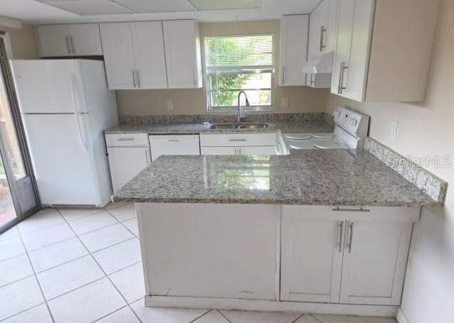 A kitchen features white cabinets, granite countertops, a white refrigerator, and a tiled floor — 188 MOONSTONE COURT, PORT ORANGE, FL