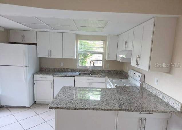 A kitchen features white cabinets, granite countertops, a white refrigerator, and a stainless steel sink — 188 MOONSTONE COURT, PORT ORANGE, FL