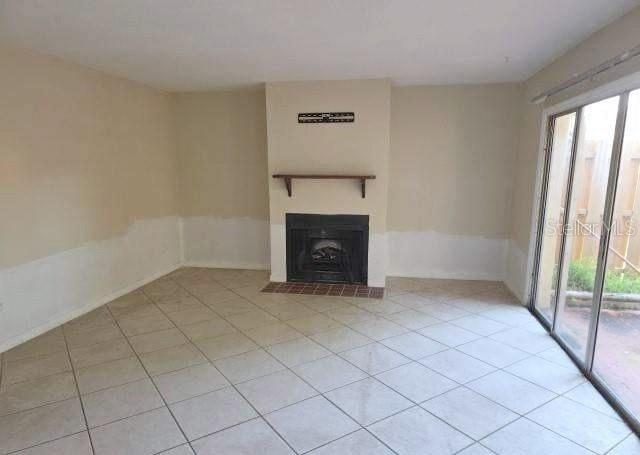 A living room with tile floors, a fireplace, a wooden mantel, and sliding glass doors — 188 MOONSTONE COURT, PORT ORANGE, FL
