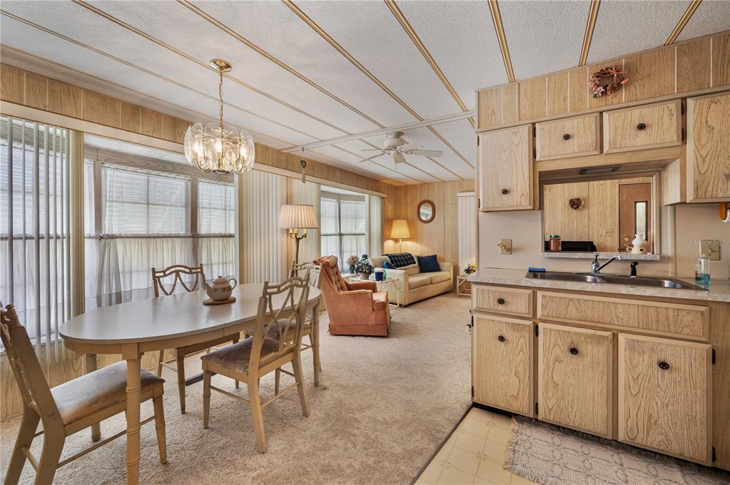 A kitchen and dining area featuring wood-paneled walls, cabinetry, a white refrigerator, and carpeted flooring — 1610 REYNOLDS ROAD UNIT 262, LAKELAND, FL