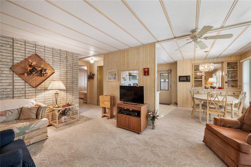 A living room features wood-paneled walls, a brick accent wall, and a drop ceiling — 1610 REYNOLDS ROAD UNIT 262, LAKELAND, FL