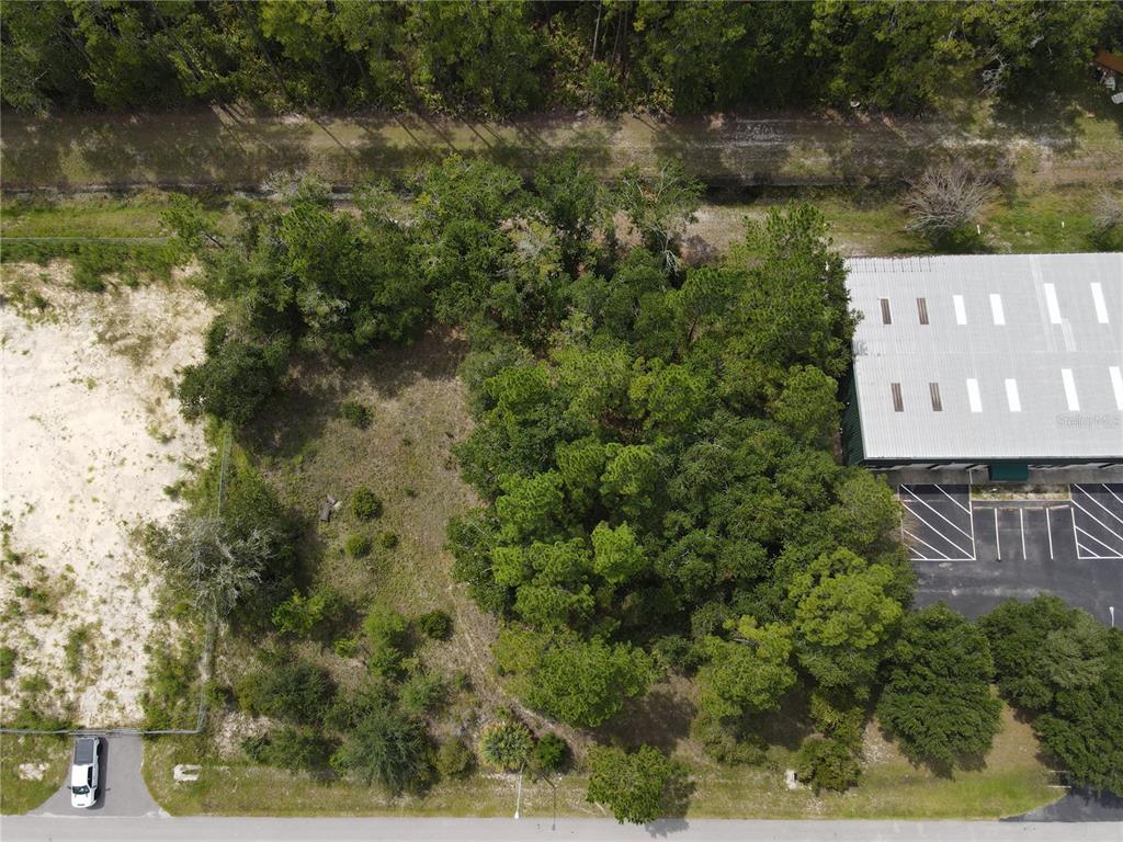 An aerial view shows a wooded, undeveloped lot adjacent to a commercial building and parking lot — LOT 4 & LOT 5 NW 16TH STREET, GAINESVILLE, FL